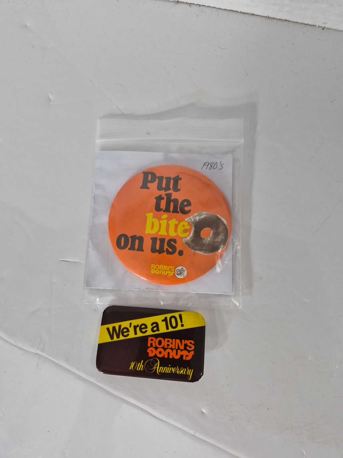 Vintage 1980s Robin’s Donuts Advertising Pinback Buttons – “Put the Bite on Us” & 10th Anniversary – Set of 2